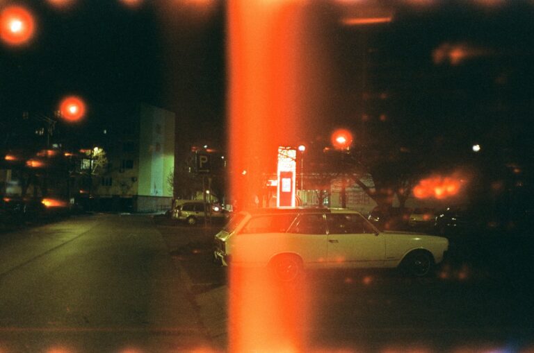 Vintage car parked on a city street at night shot on film with a light leak