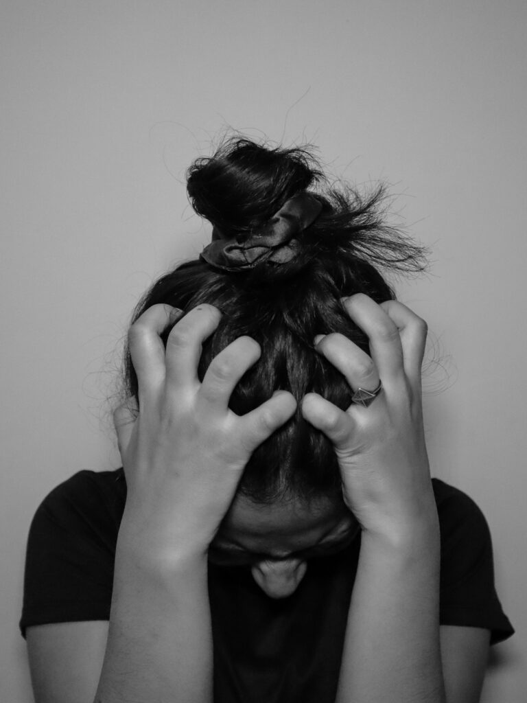 Black and white close-up of a woman with windblown hair in a dramatic portrait