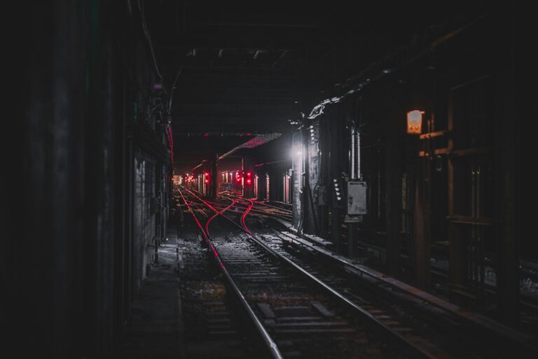 Dark subway tunnel with red signal lights glowing along the train tracks