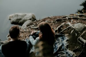 Two people sitting together on rocks overlooking a misty landscape