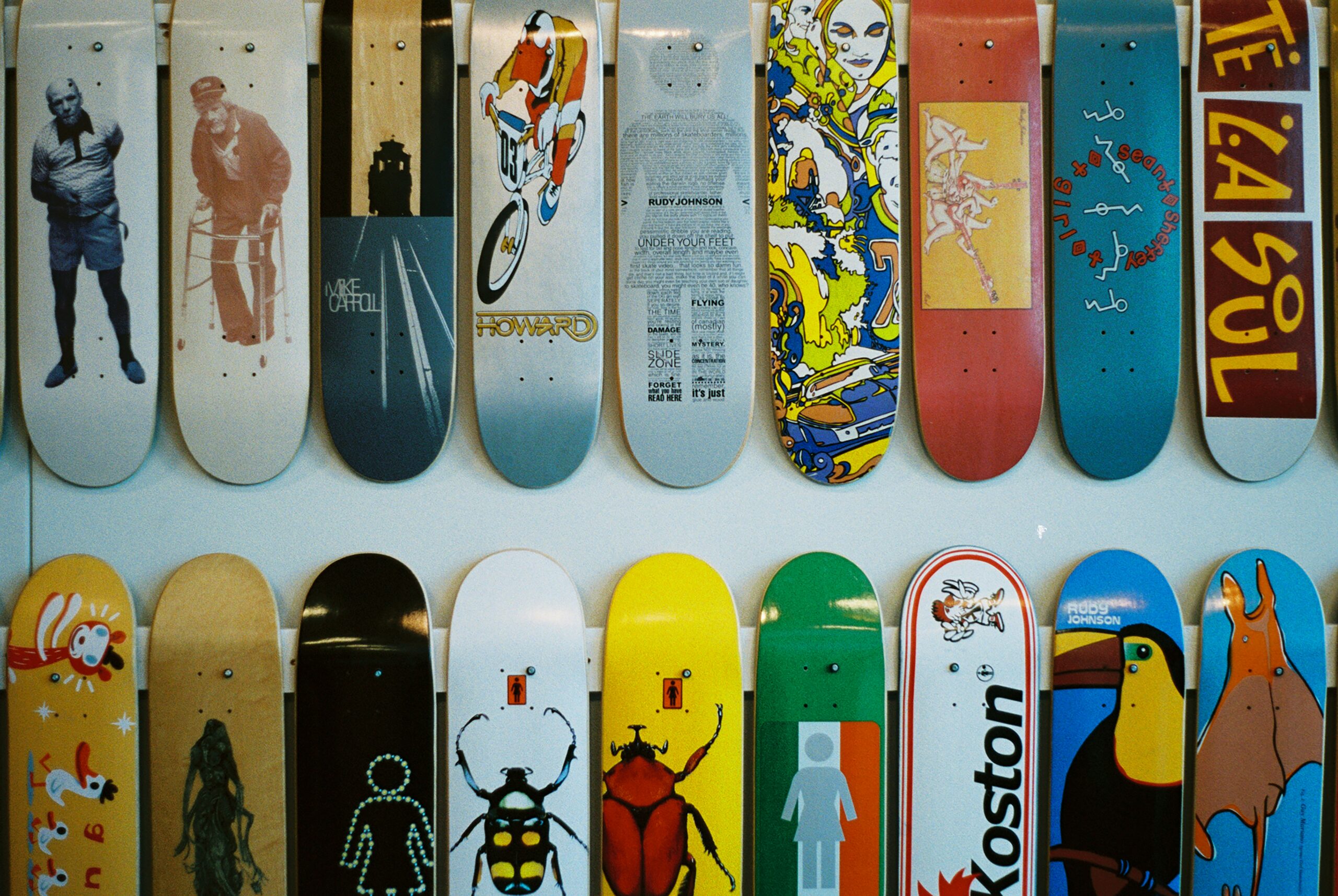 Colorful collection of skateboard decks with various artistic designs displayed on a wall