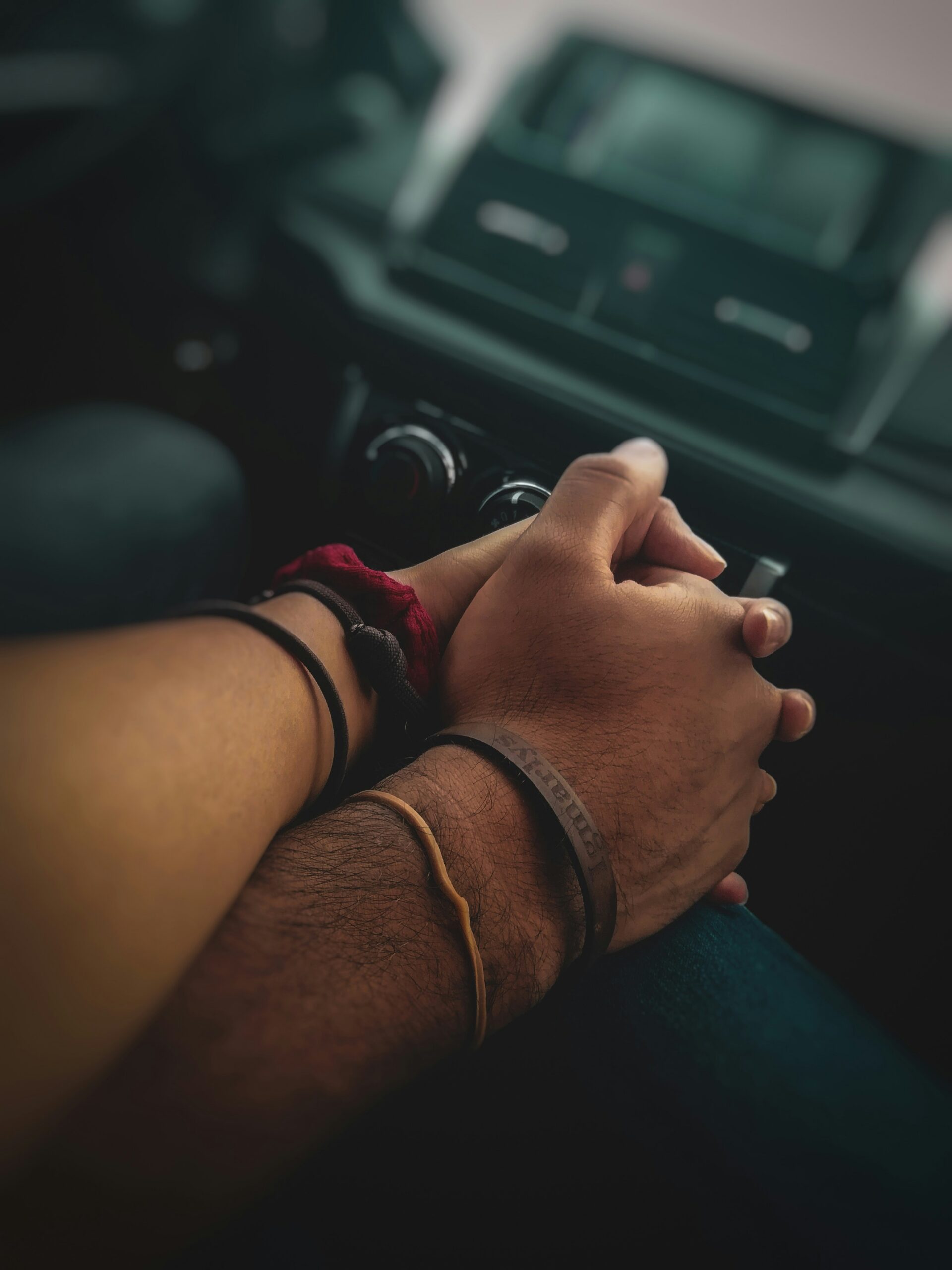 Couple holding hands in a car with bracelets on their wrists
