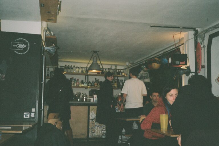 Young people socializing in a dimly lit bar with bottles lining the shelves behind them