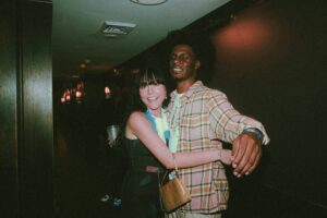 Young man and woman smiling together at a social event in a film-style photograph