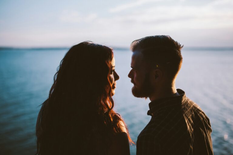 Silhouette of a couple standing together by the water at sunset