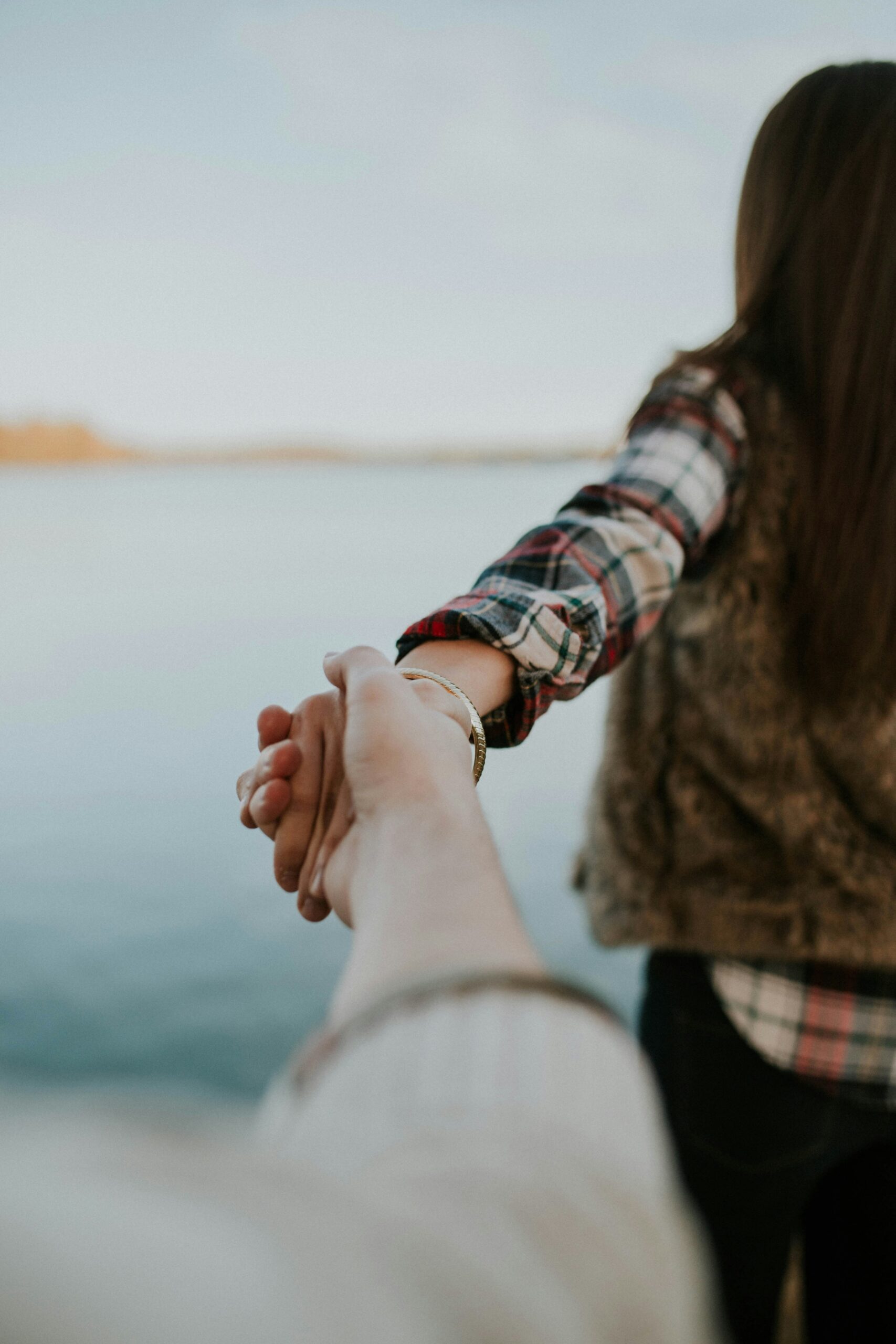 Couple holding hands by a lake at sunset, reflecting the deep emotional bonds of soul ties