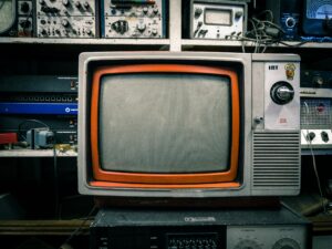 Vintage orange television set against a colorful background, representing how media like Love Island shapes desire and relationships