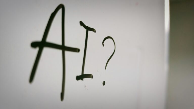 The letters AI with a question mark written in bold black text, exploring the harmful trend of AI-generated pornography