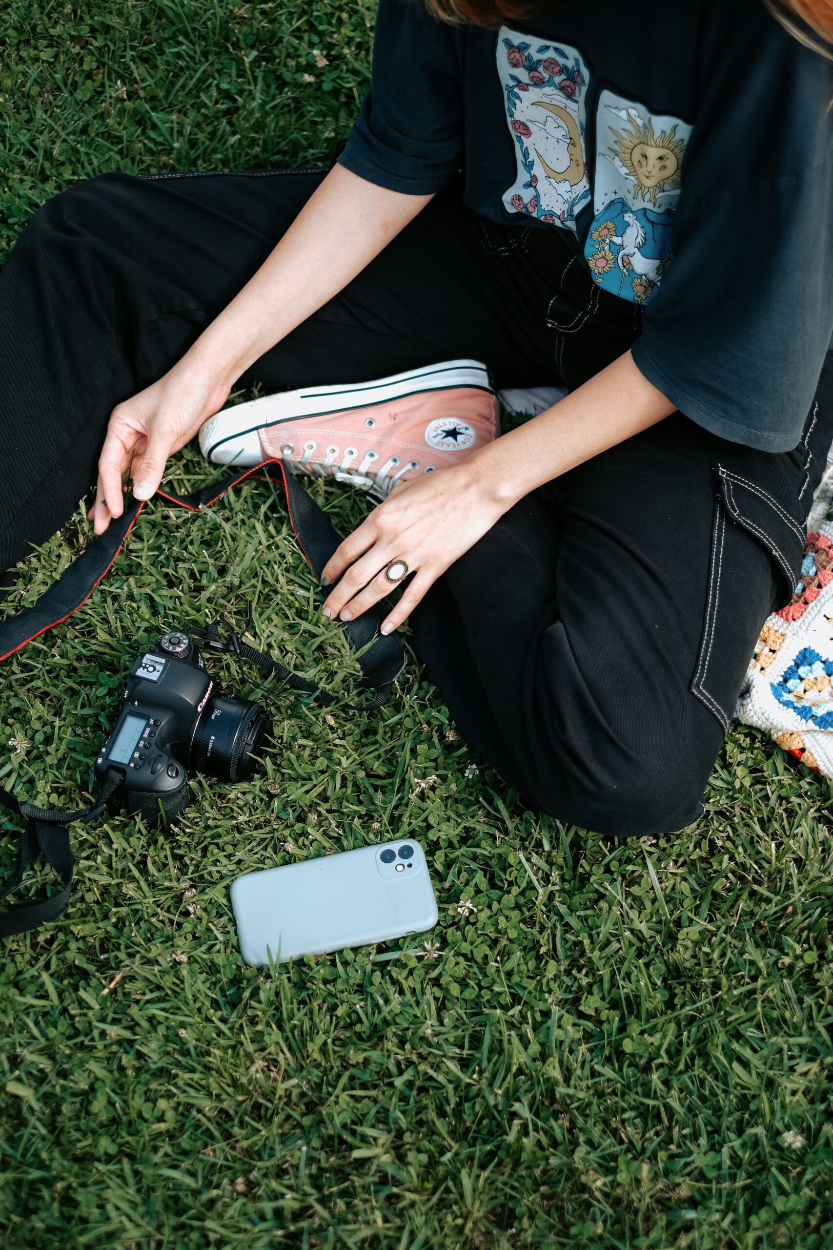 Hands resting on grass beside sneakers and a camera, representing everyday life and the subtle lies about sexual temptation