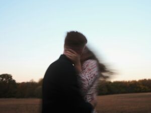 Silhouette of a person walking alone along a calm shoreline at golden hour