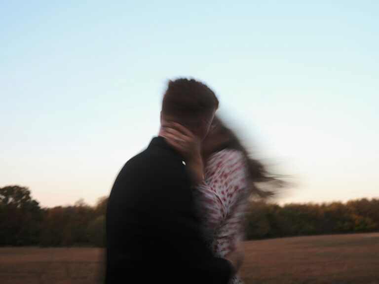Silhouette of a person walking alone along a calm shoreline at golden hour