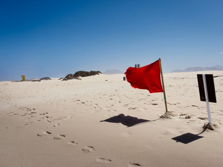 Red flag planted in the sand on a beach, symbolizing dating red flags and wild Christian dating stories