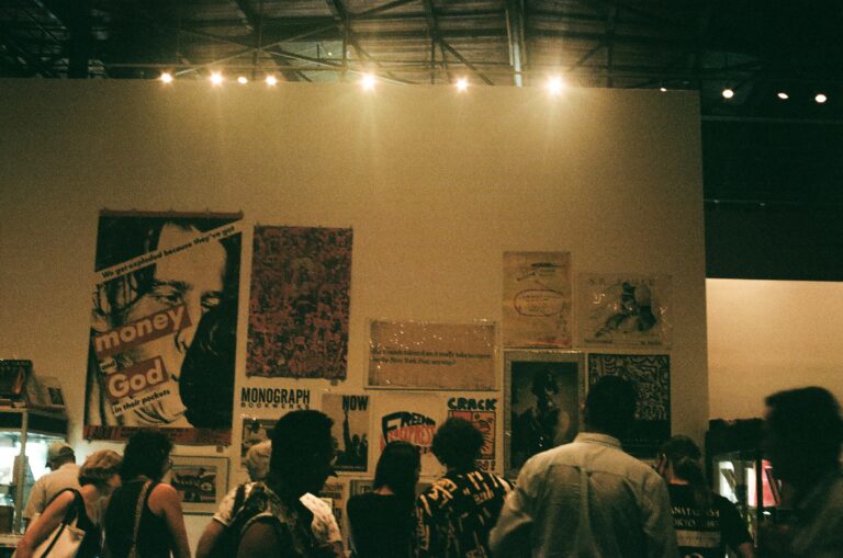 People gathered in a dimly lit room with posters covering the walls