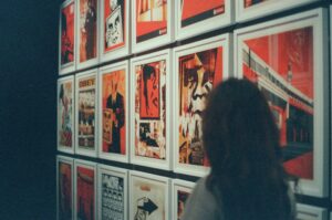 Silhouette of a woman standing in front of a wall of red framed artwork