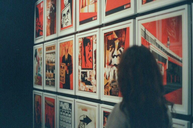 Silhouette of a woman standing in front of a wall of red framed artwork