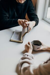 Woman holding an open book and a cup of coffee at a table