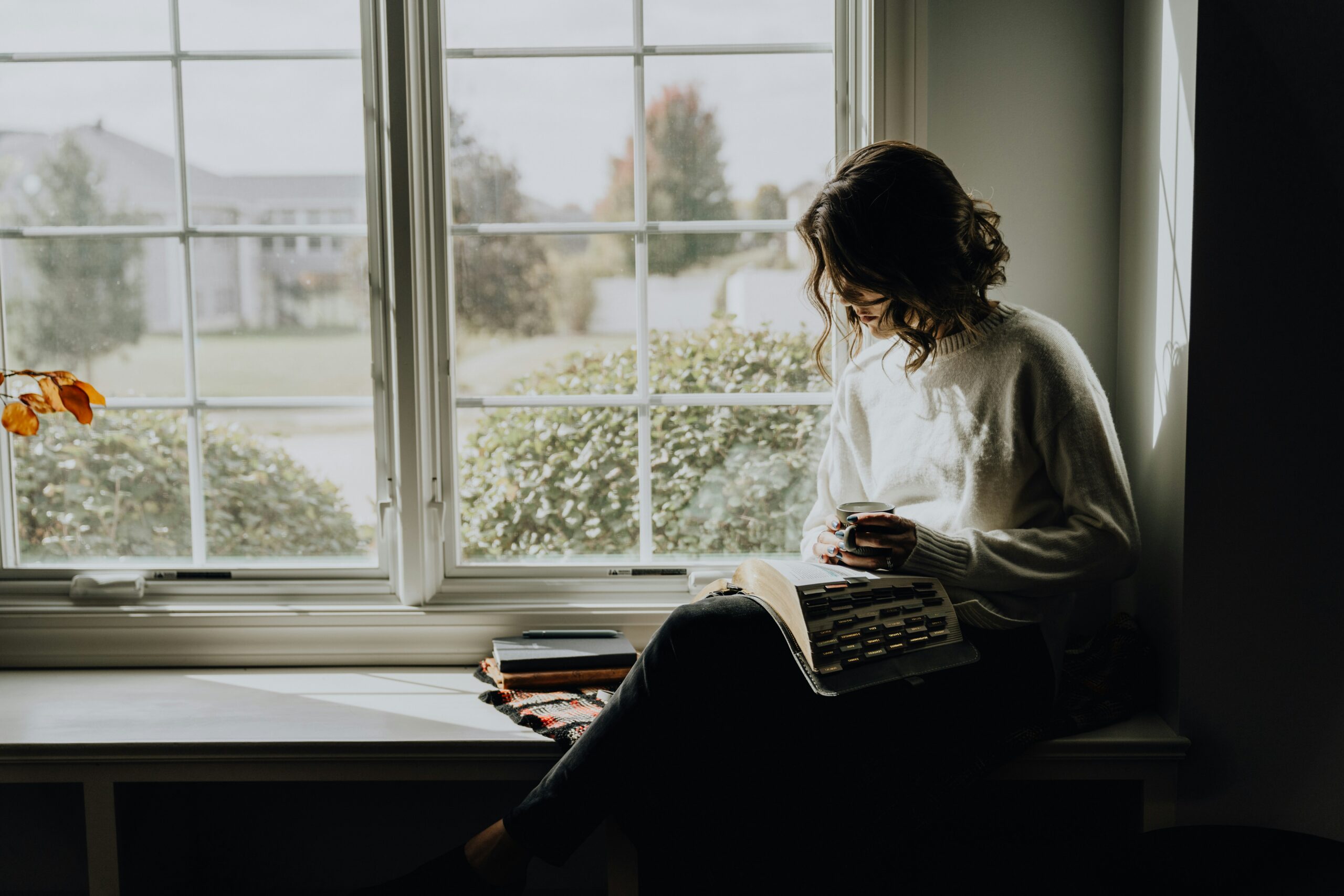 Woman sitting alone by a window in soft natural light