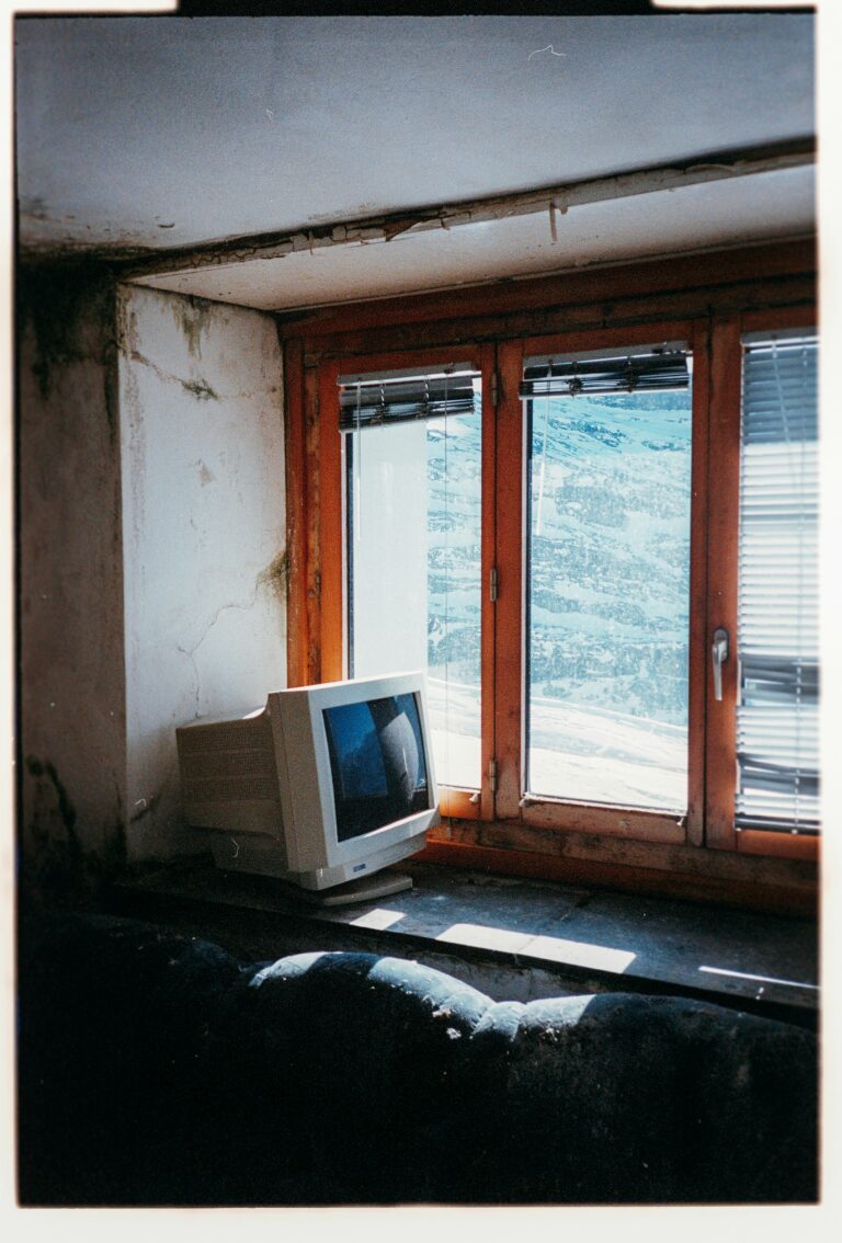 Abandoned room with peeling walls and an old computer monitor sitting on the floor by a window