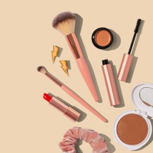 Flat lay of makeup brushes, lipstick, and beauty products arranged on a neutral background, representing modesty, beauty, and identity