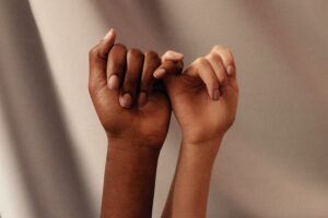Two women linking pinky fingers in a pinky promise, representing sisterhood and honest conversation among Christian women about modesty