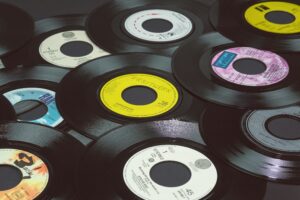 Stack of vintage vinyl record singles, including a yellow 45 rpm single