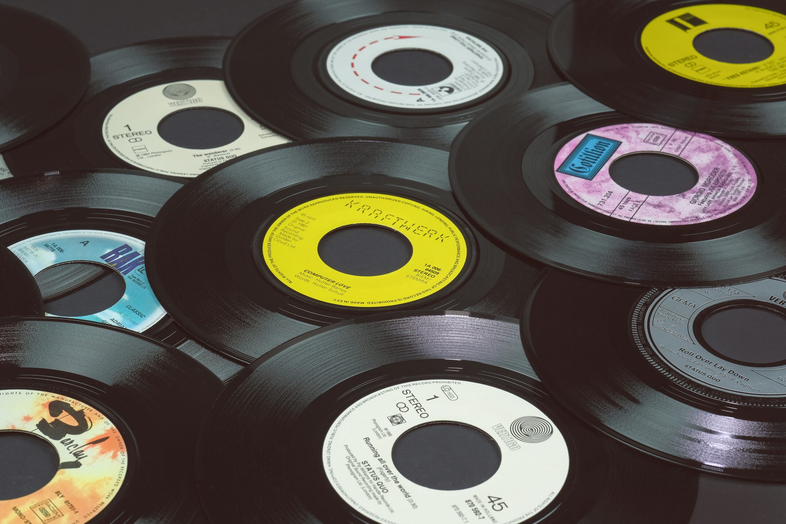 Stack of vintage vinyl record singles, including a yellow 45 rpm single