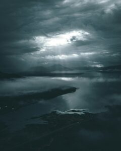 Misty sea with a distant island under a grey, cloudy sky