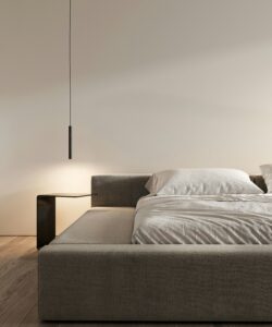 Neatly made bed in a calm minimalist bedroom lit by a single pendant lamp