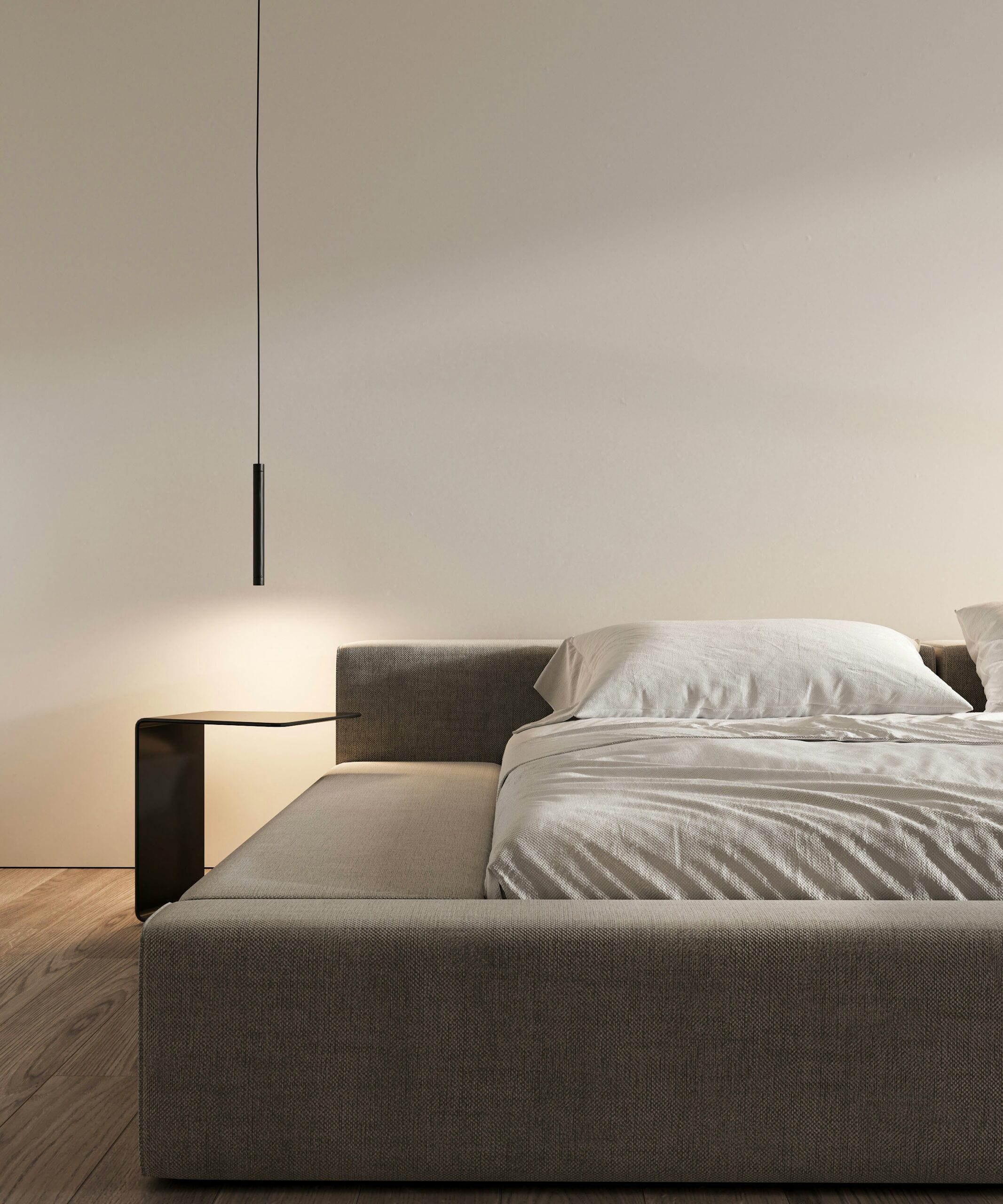 Neatly made bed in a calm minimalist bedroom lit by a single pendant lamp