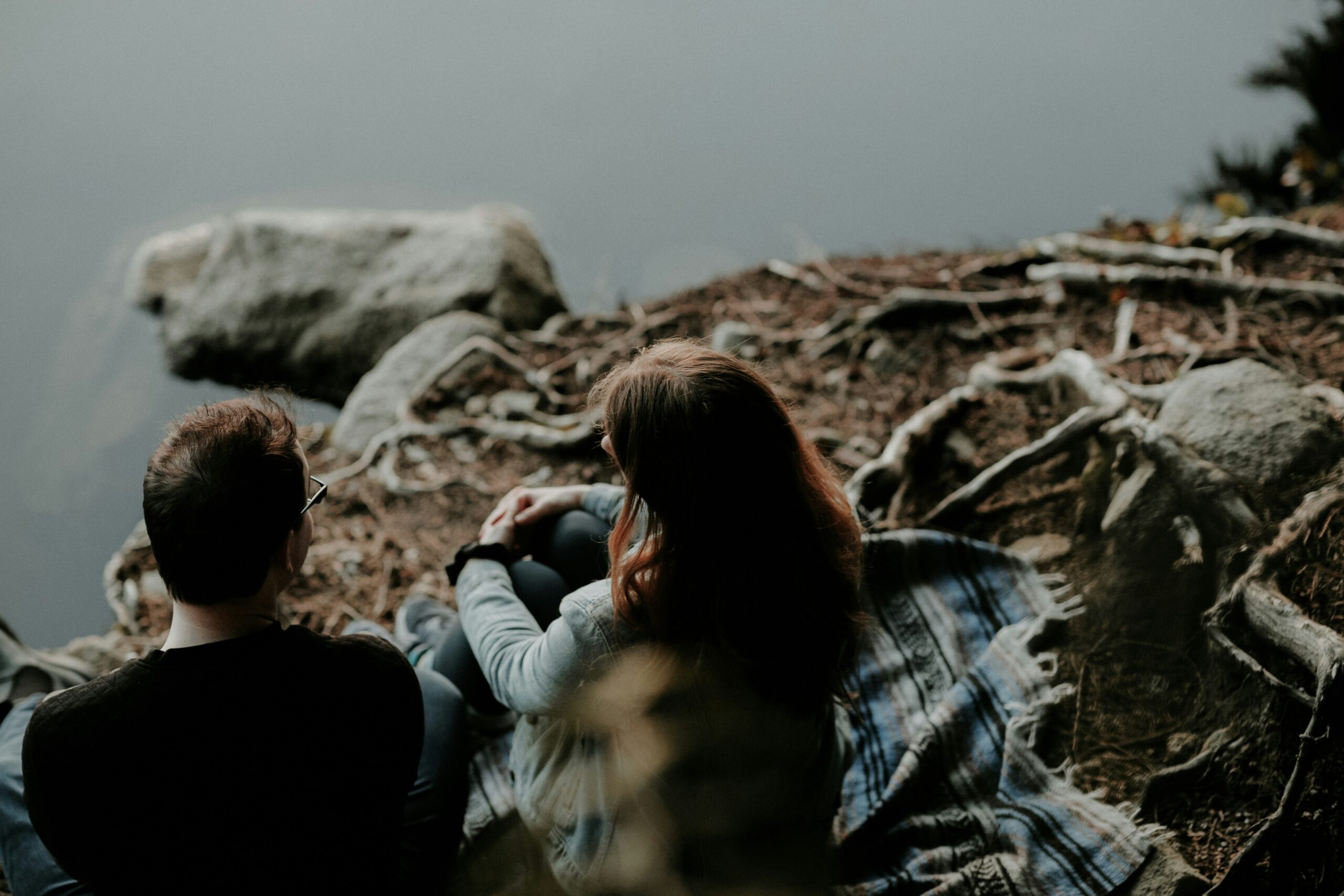 Couple sitting close together on a rocky overlook having a quiet, serious conversation