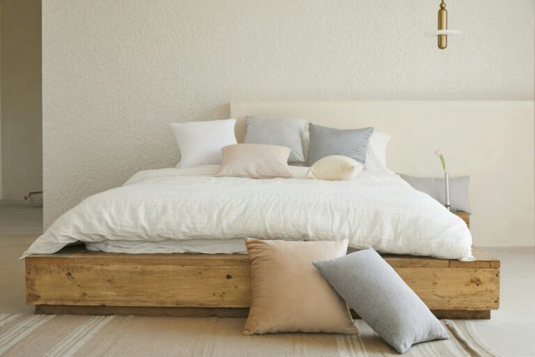 Minimalist bedroom with a wooden platform bed and white linen bedding, representing mismatched sex drives in marriage