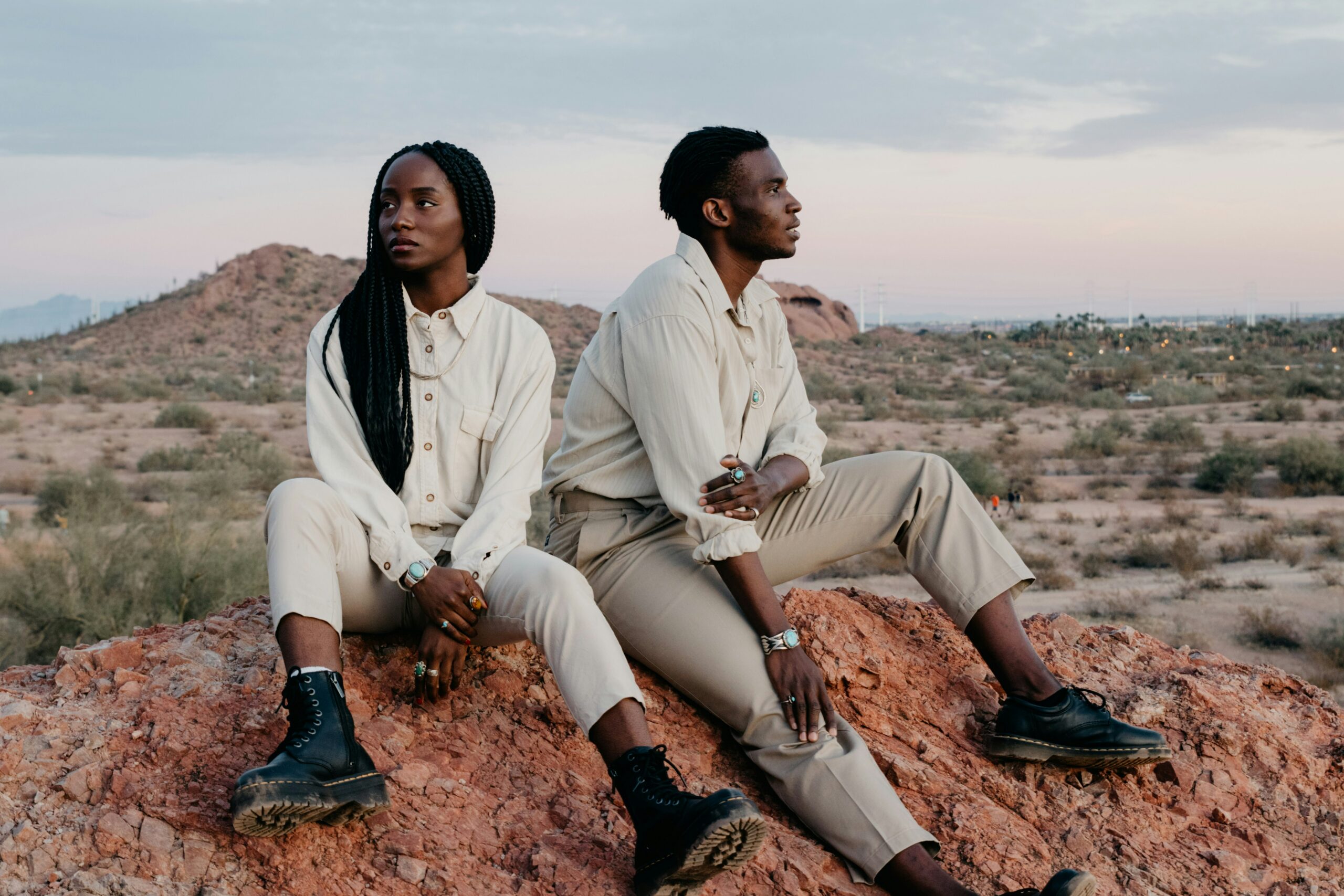 Couple sitting together on a desert outcrop at golden hour, talking about where their relationship is going