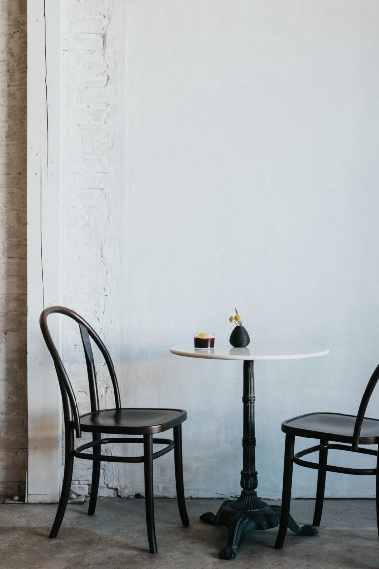 Two cafe chairs at a marble table with a single coffee, Let's Talk About It podcast episode on how guys are wired