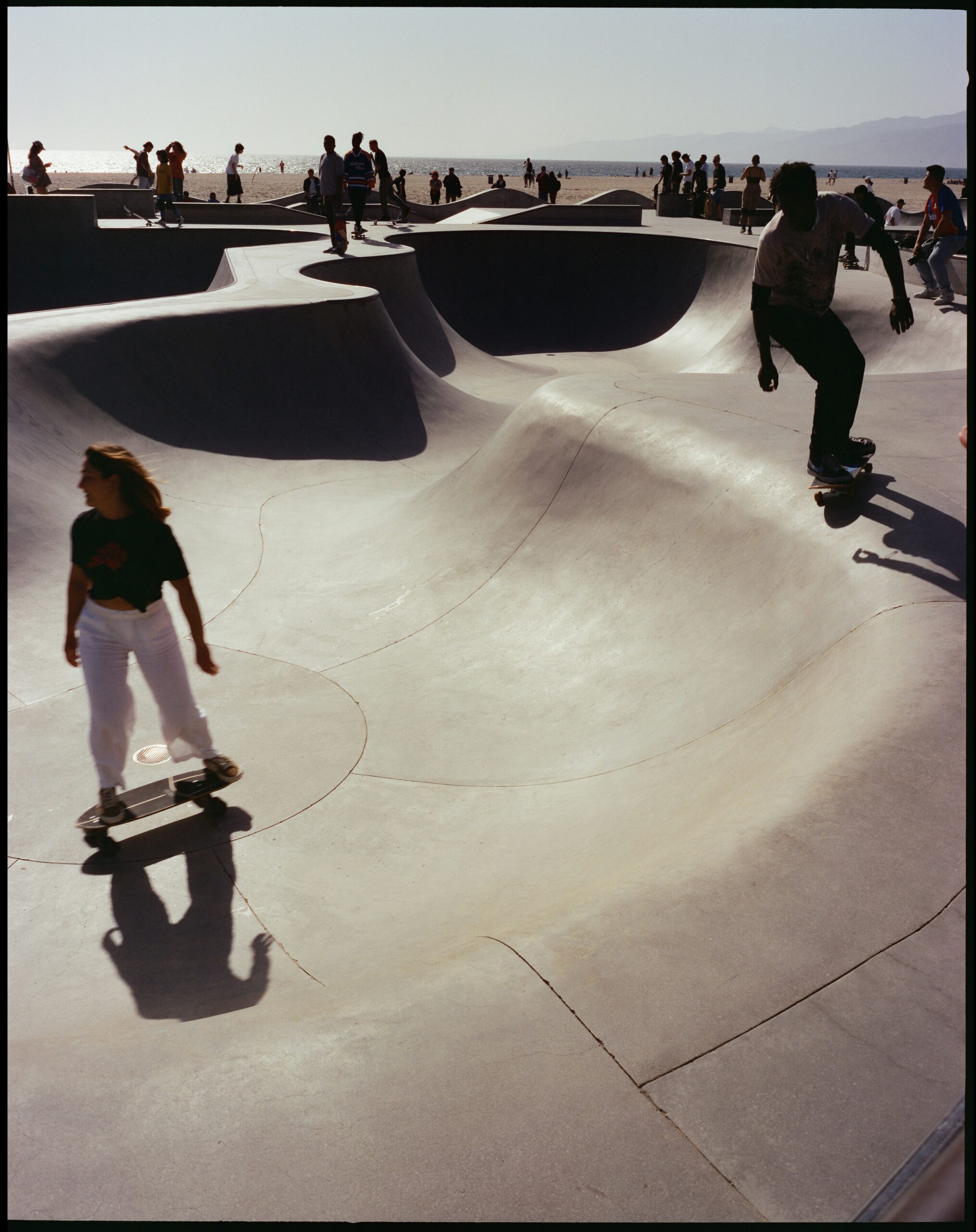 Young man and woman skateboarding at a sunny beachside skate park, an everyday moment of noticing without lusting